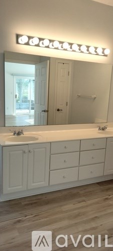A bathroom with a white vanity and a mirror with lights.