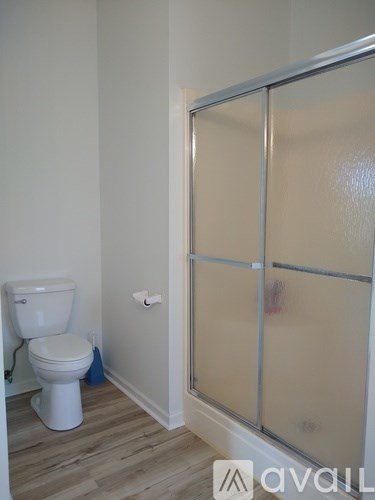 A white toilet sits in a bathroom next to a glass shower door.
