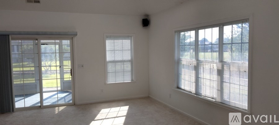 A room with a sliding glass door and a window with blinds.