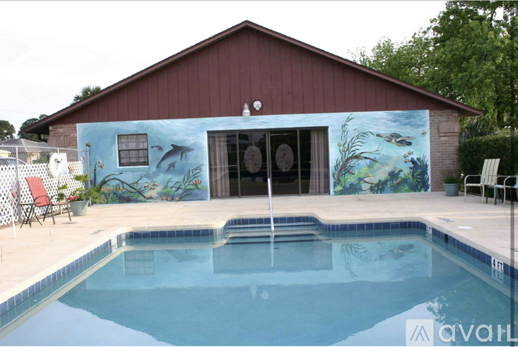 A pool in front of a house with a mural on the wall.