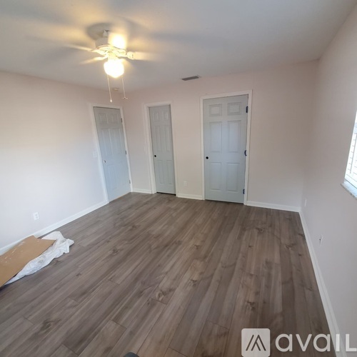 A room with wooden flooring and three doors.