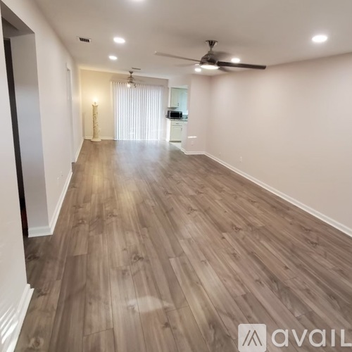 A spacious room with wooden flooring and a ceiling fan.