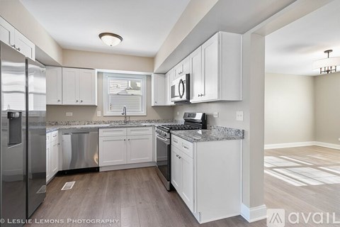 A modern kitchen with white cabinets and stainless steel appliances.