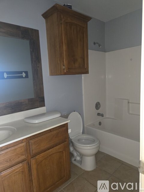 A bathroom with a toilet, sink, and wooden cabinet.