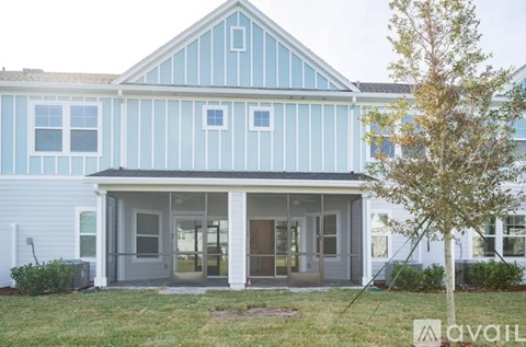 A blue and white building with a tree in front.