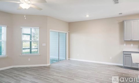 A spacious room with a ceiling fan and sliding glass doors.