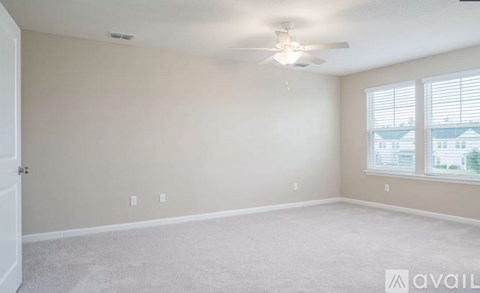 A room with a ceiling fan and carpeted floor.