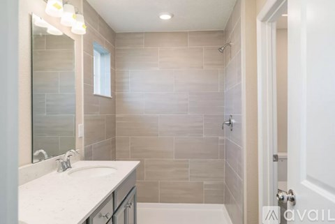 A bathroom with a sink, mirror, and tiled walls.