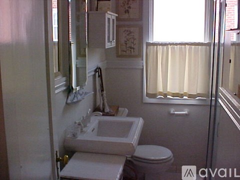 A bathroom with a toilet, sink, and mirror.