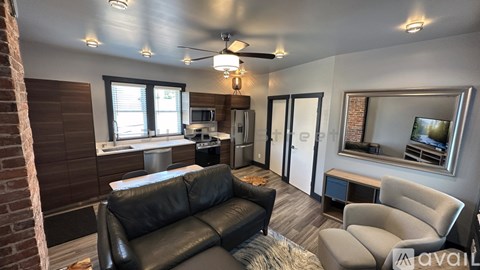 A living room with a black leather couch and a grey armchair.