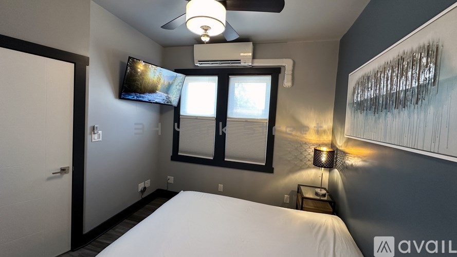 A bedroom with a bed, a ceiling fan, and a television.