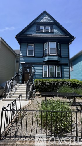 A blue house with a black fence in front.
