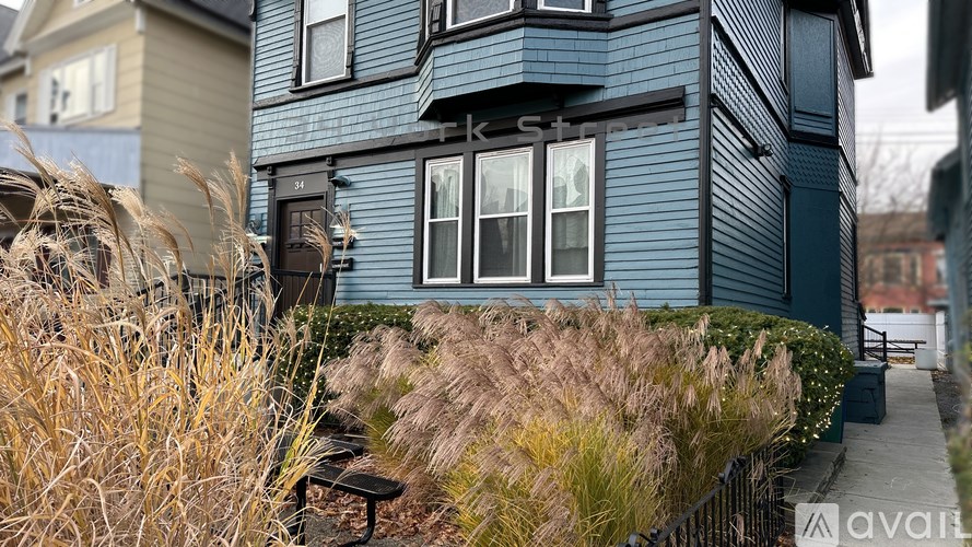A blue house with a black fence and a bench in front of it.