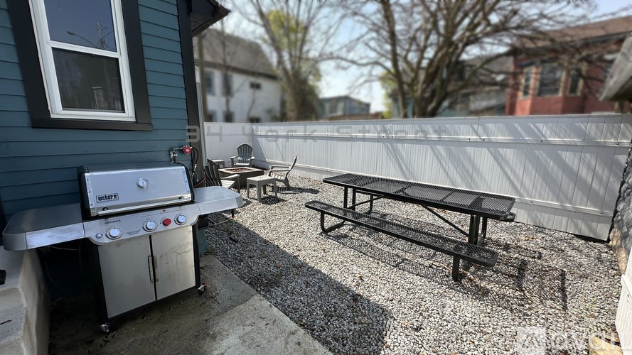 A BBQ grill is on a patio with a picnic table.