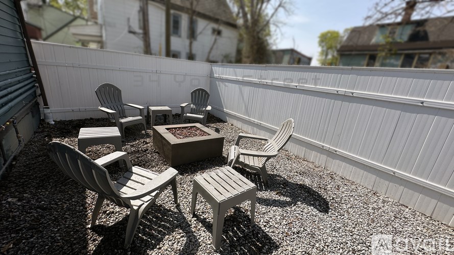 A patio with white chairs and a table.