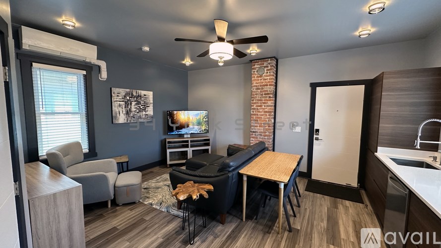 A living room with a brick fireplace and a ceiling fan.