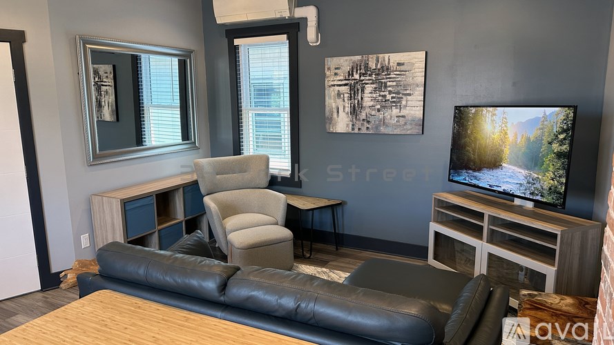 A living room with a black leather couch and a television on a wooden stand.