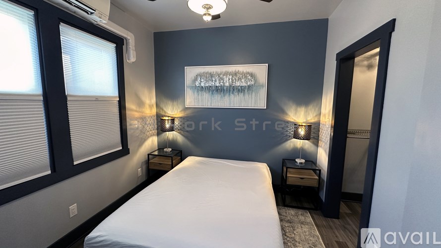 A bedroom with a bed, two lamps, and a framed picture on the wall.