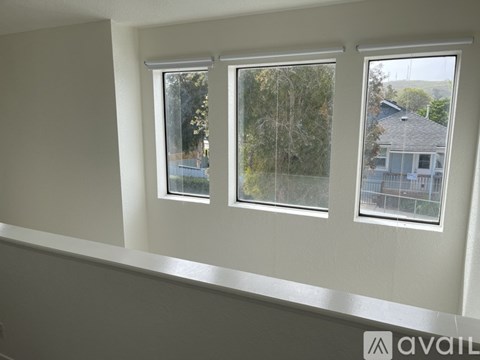 Three windows in a room with a view of a house and trees outside.