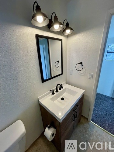 A bathroom with a sink, mirror, and lighting fixtures.