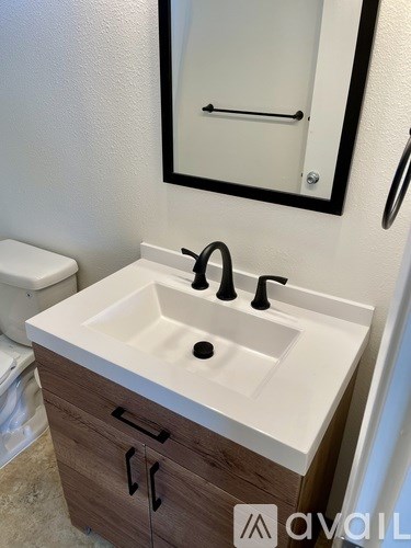 A white sink with a black faucet is in a bathroom with a mirror above it.