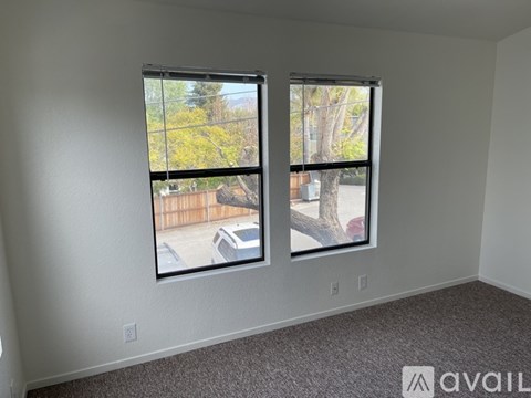 A room with two windows overlooking a street.