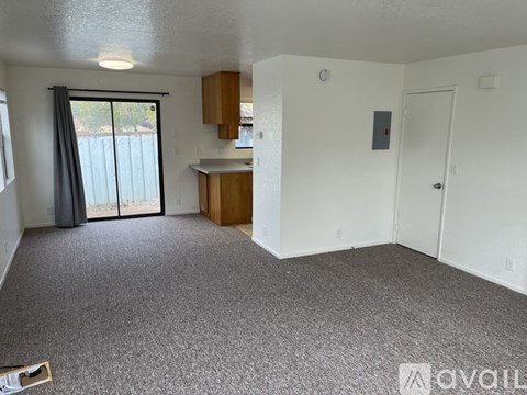 A carpeted room with a sliding glass door leading to a balcony.