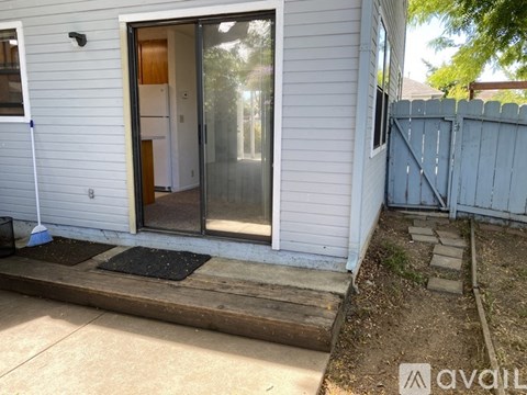 A white house with a glass door and a black mat on the concrete.