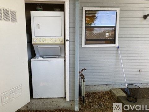 A white refrigerator is in a small outdoor shed.