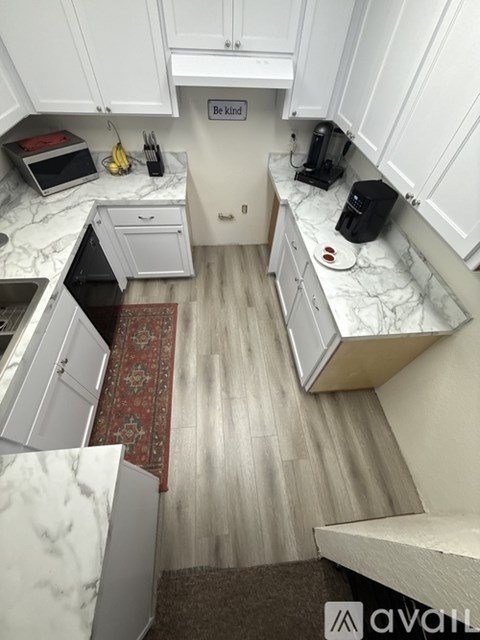 A kitchen with white cabinets and a marble countertop.