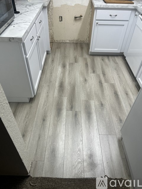 A kitchen with white cabinets and a wooden floor.