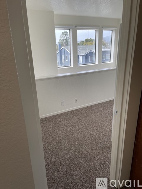 A room with a carpeted floor and a window overlooking houses.
