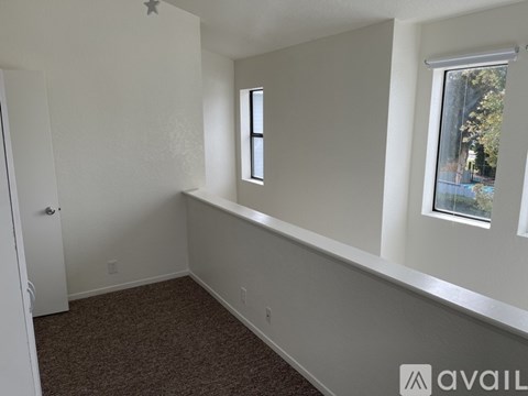 A room with a carpeted floor, a window, and a door.