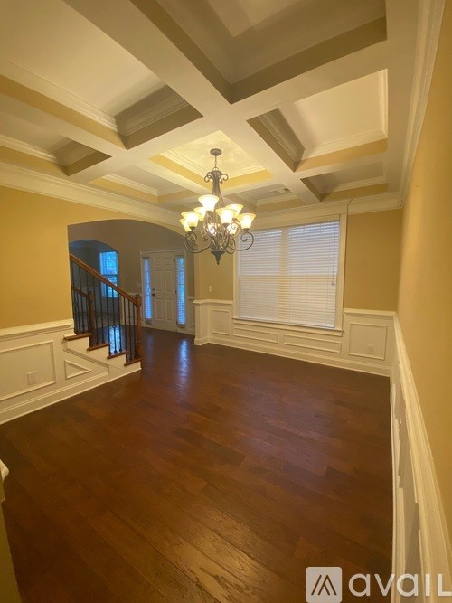 A spacious room with wooden floors and a chandelier.