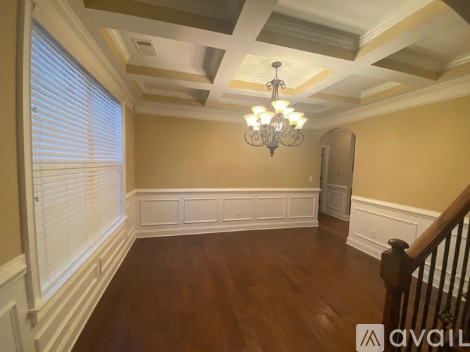 A chandelier hangs in a room with wooden floors and white trim.