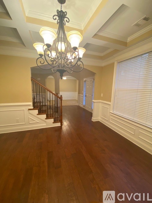 A chandelier hangs over a wooden staircase.