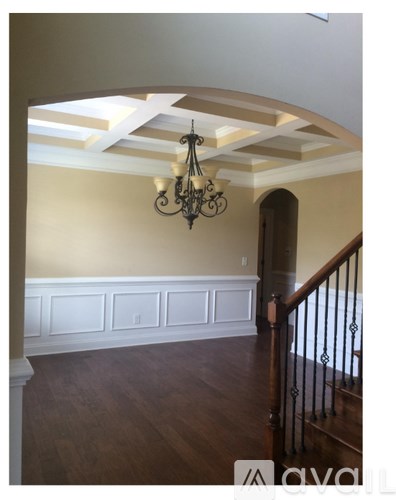 A chandelier hangs over a staircase with white trim.