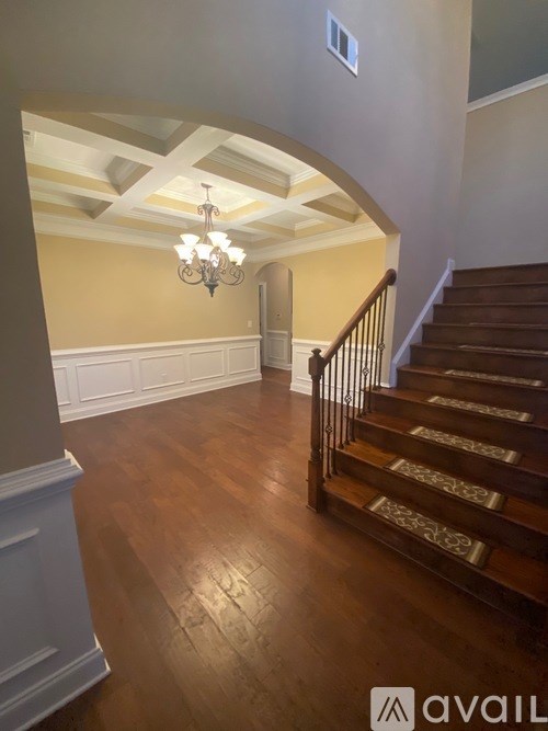 A staircase with a chandelier and a wall on the side.