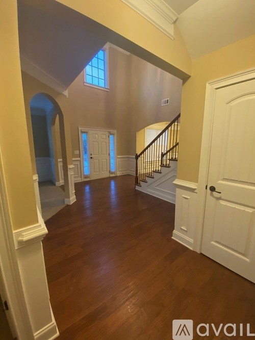 A spacious room with wooden floors and a staircase with a railing.