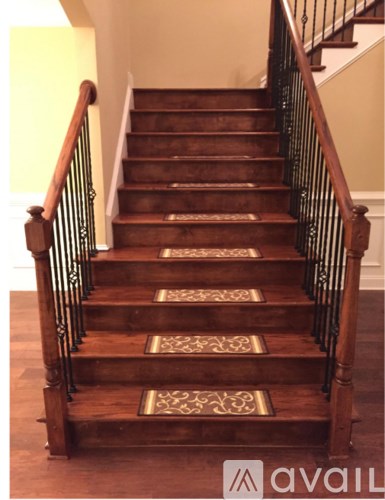 A wooden staircase with a metal railing and decorative tiles on the steps.
