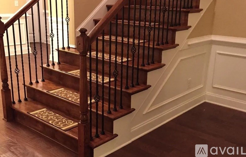 A wooden staircase with a white baseboard and a black railing.