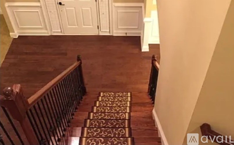 A staircase with a wooden banister and a patterned rug.