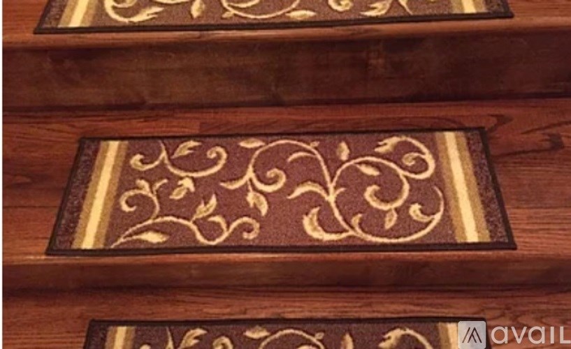A brown and gold patterned doormat on a wooden floor.