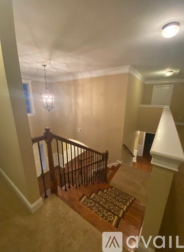 A hallway with a light hanging from the ceiling and a rug on the floor.