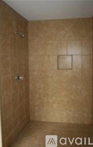 A bathroom with brown tiles and a shower.