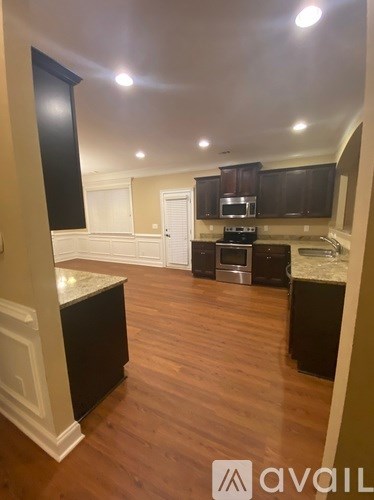 A kitchen with dark wood floors and a marble island.
