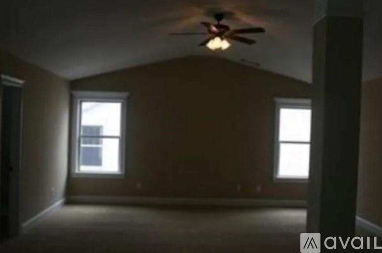 A room with a ceiling fan and two windows.