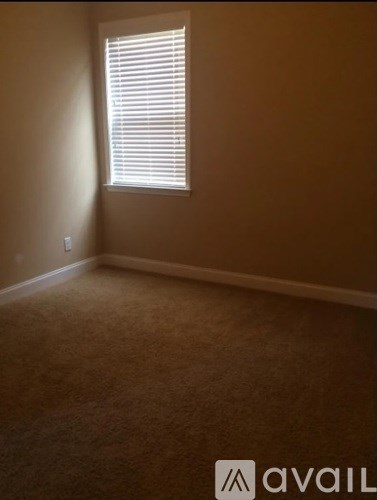 A room with a carpeted floor and a window with blinds.