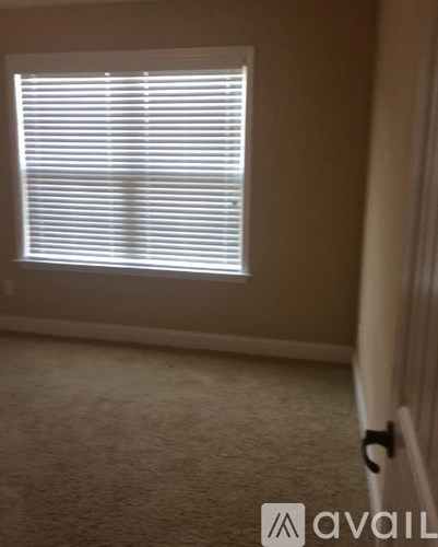 A room with a carpeted floor and a window with blinds.