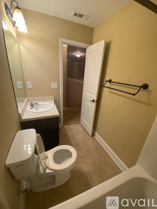 A bathroom with a toilet, sink, and mirror.